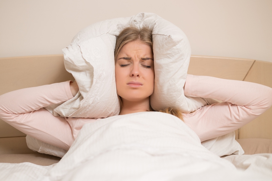 woman covering ears due to loud air conditioner making noise